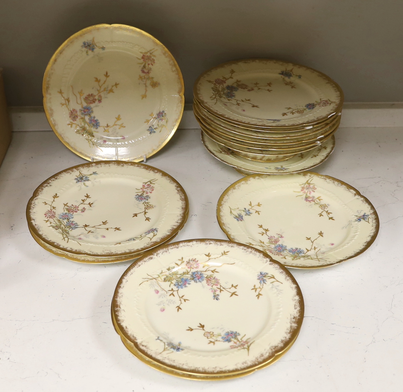 Thirteen Limoges style porcelain dessert plates, two on pedestal bases, gilt decorated with cornflowers etc., 24.5cm diameter